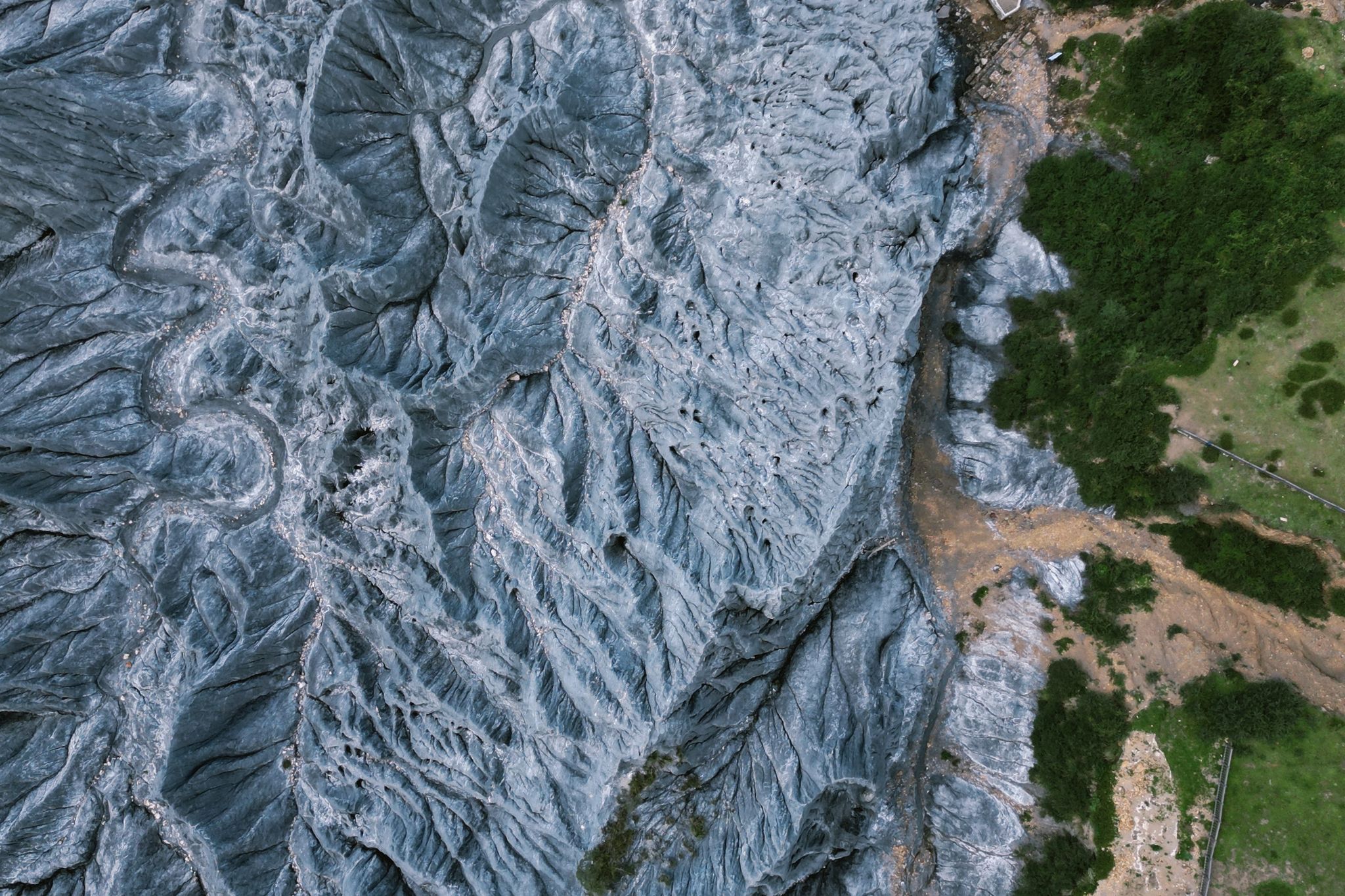 Drone shot capturing dramatic glacial terrain meeting lush greenery, showcasing nature's contrast.
